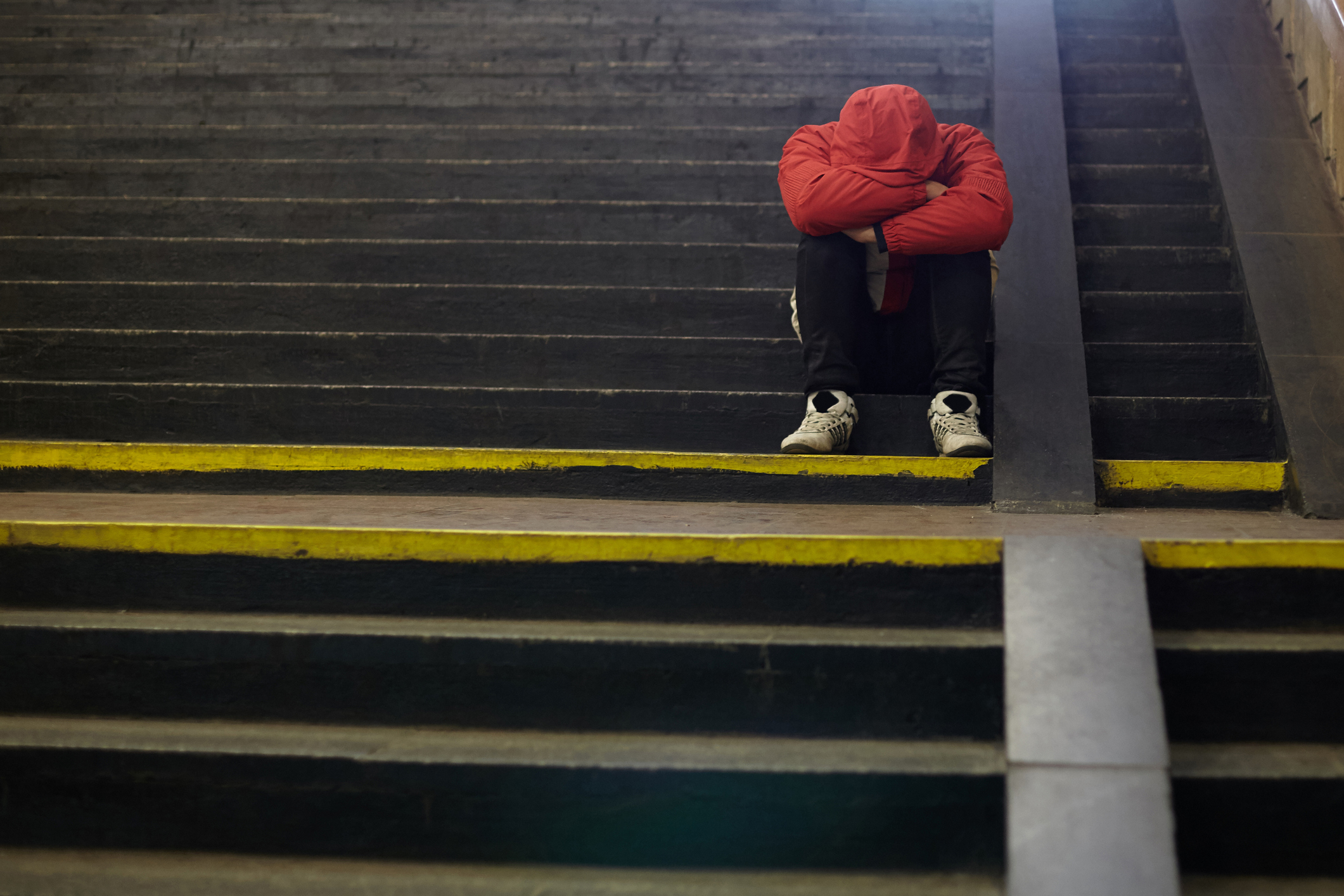 teenager sitting on stairs with head down